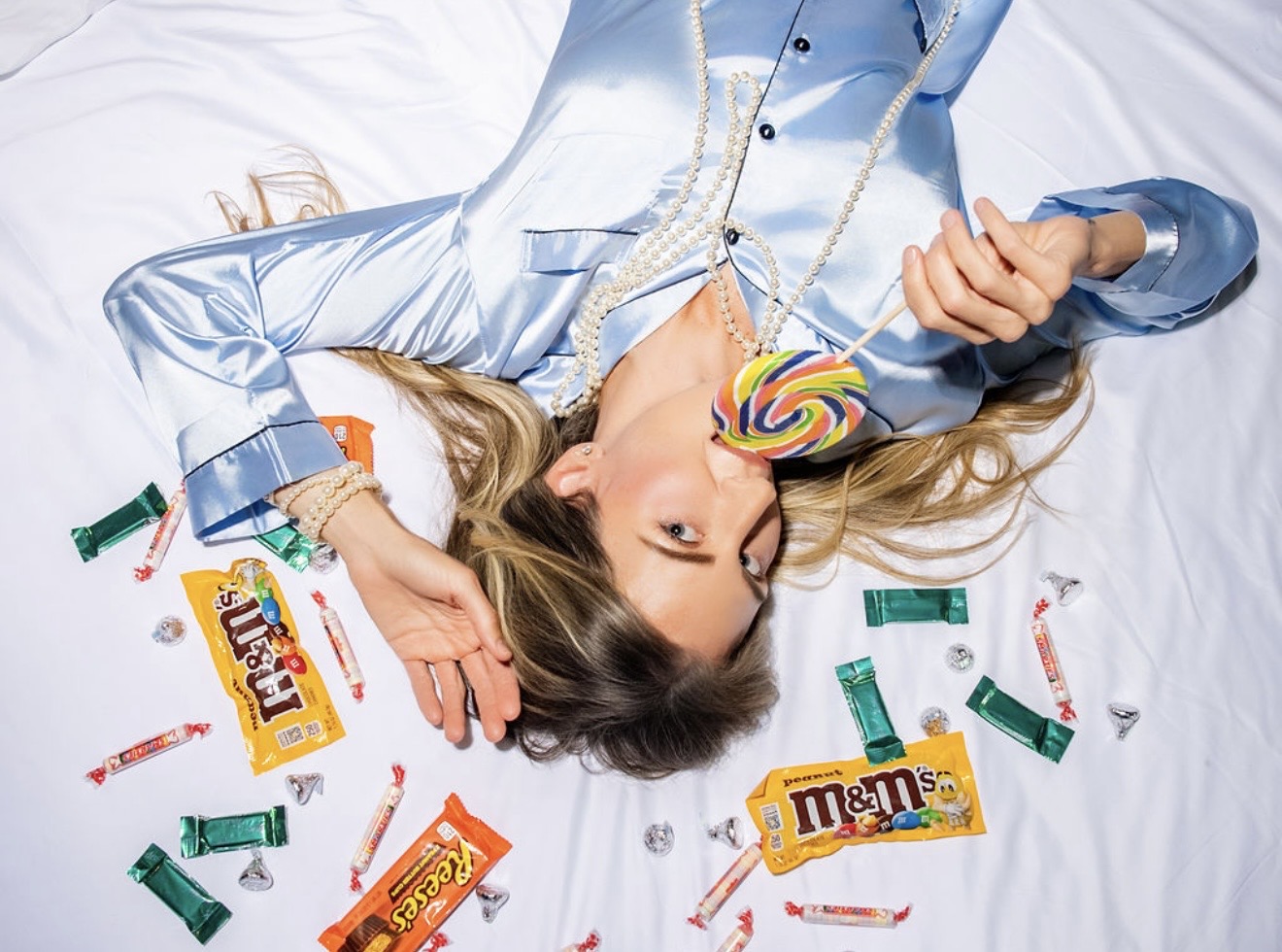 Crystal reclining on the hotel bed among colorful candy